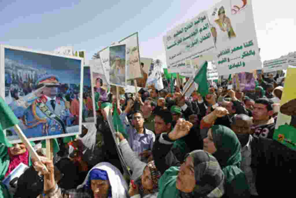 Pro-government supporters hold posters of Libyan leader Muammar Gaddafi as they chant slogans during a demonstration in Tripoli to counteract online calls for an anti-government 'day of rage,' February 17, 2011