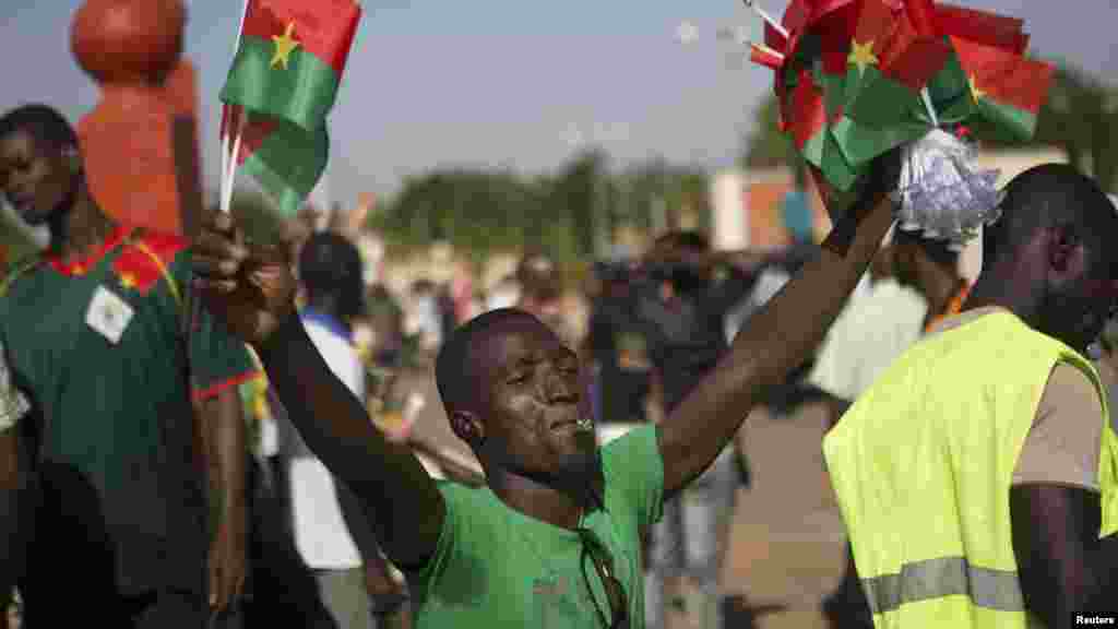 Un vendeur de drapeau grimace au cours d'une marche contre le président du Burkina Faso Blaise Compaoré à Ouagadougou, capitale du Burkina Faso, le 29 Octobre, 2014. Mardi marqué le début d'une campagne de désobéissance civile par les partis d'opposition après que le gouvernement a demandé à l'Assemblée nationale d'ordonner un référendum sur modification de la constitution pour laisser Compaoré briguer un nouveau mandat l'année prochaine plutôt que de démissionner. REUTERS / Joe Penney 