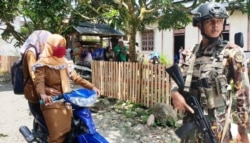 Dua perempuan melintas di depan aparat keamanan di Poso. (Foto: Yoanes Litha/ dok)