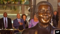 South African President Jacob Zuma, second left, in background with a bust of former South African President Nelson Mandela, center, outside Parliament before giving the State of the Nation address in the city of Cape Town, South Africa, June 17, 2014.