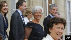 French Finance Minister Christine Lagarde, center, stands with ministers as she leaves the Elysee Palace in Paris, after the weekly Cabinet meeting, June 29, 2011