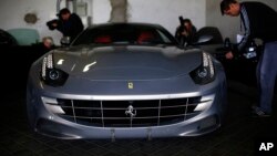 Members of the media take images of one of the two Ferrari luxury cars donated by Spanish former King Juan Carlos to the National Heritage, in Madrid, Oct. 19, 2015.