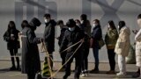Security guards set up the barricade line as people line up to get a swab for the COVID-19 test to meet traveling requirements at a mobile coronavirus testing facility outside a commercial office buildings in Beijing, Jan. 16, 2022. 