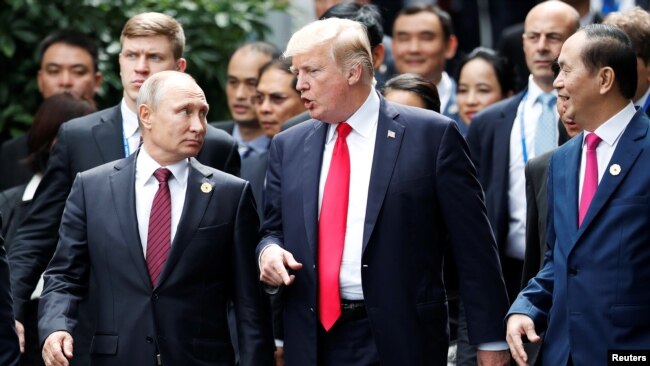 FILE - U.S. President Donald Trump and Russia's President Vladimir Putin talk as Vietnam's President Tran Dai Quang, right, looks on, during the photo session at the APEC Summit in Danang, Vietnam, Nov. 11, 2017.