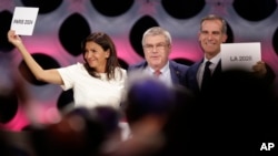 International Olympic Committee President Thomas Bach stands between Paris Mayor Anne Hidalgo, left, and Los Angeles Mayor Eric Garrett at the end of the IOC session in Lima, Peru, Sept. 13, 2017. 