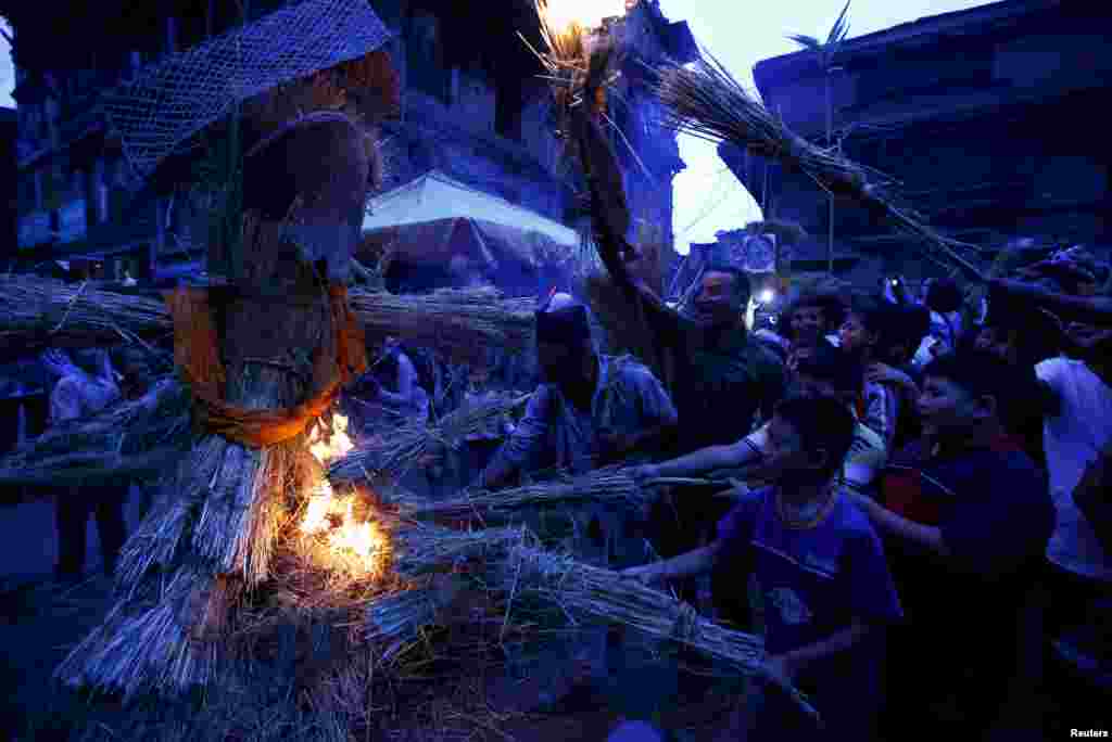 네팔 고대 도시 바크타푸르에서 열린 간타카르나 축제에서 참가자들이 악마 모형에 불을 붙이고 있다.