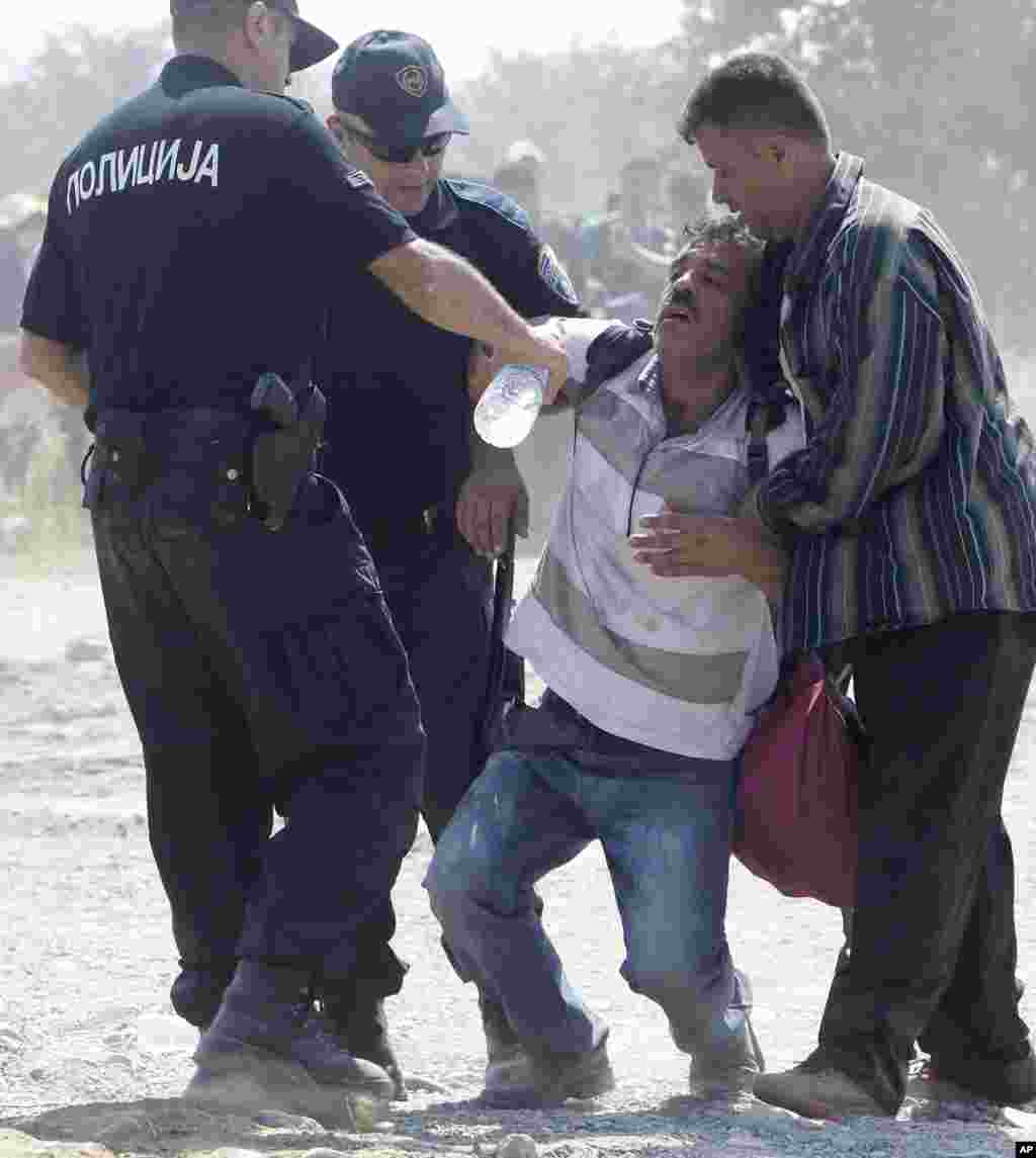 Macedonian policemen help a dehydrated migrant after crossing the border from Greece to Macedonia, near the southern town of Gevgelija.