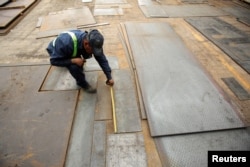 FILE - An employee measures steel plates at Kalisch Steel factory in Ciudad Juarez, Mexico, March 27, 2018.