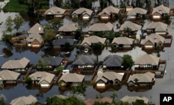 FILE - Homes are surrounded by water from the flooded Brazos River in the aftermath of Hurricane Harvey, in Freeport, Texas, Sept. 1, 2017.