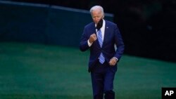 FILE - President Joe Biden takes off his mask as he walks from Marine One on the South Lawn of the White House in Washington, Oct. 5, 2021, after returning from a trip to Michigan to promote his infrastructure plan.