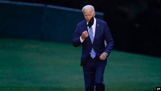 FILE - President Joe Biden takes off his mask as he walks from Marine One on the South Lawn of the White House in Washington, Oct. 5, 2021, after returning from a trip to Michigan to promote his infrastructure plan.