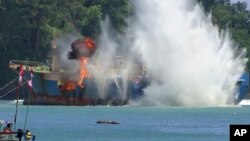 FILE - In this image made from video, an illegal fishing vessel that was seized by Indonesia’s Navy is sunk in the waters off Pangandaran, West Java, Indonesia, March 14, 2016. 