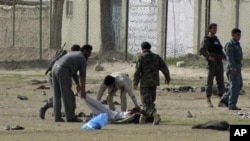 Afghan policemen and security personnel pick up a dead body after a suicide attack at an army recruitment center in Kunduz, March 14, 2011.