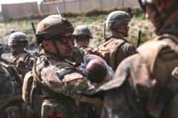 Seorang Penerbang AS menghibur seorang bayi selama evakuasi di Bandara Internasional Hamid Karzai di Kabul pada 20 Agustus 2021. (Foto: AFP/Mark Andries/Korps Marinir AS)