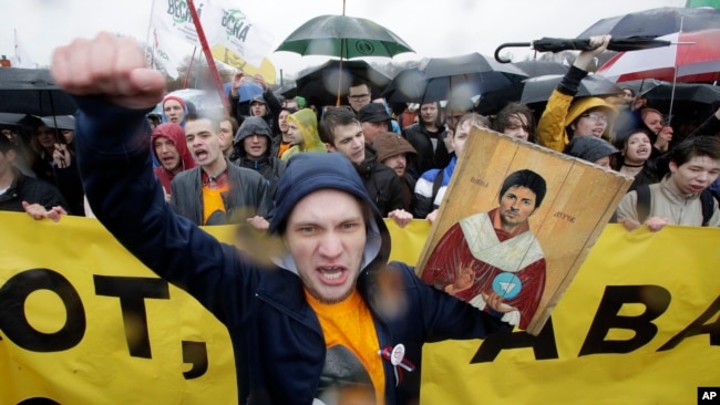 FILE - A man shouts while holding a portrait of messaging app Telegram co-founder Pavel Durov designed as an icon, to protest the blocking of the app in Russia, during a May Day rally in St. Petersburg, Russia, May 1, 2018.