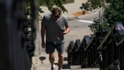 A pedestrian uses his phone in Kilbourn Reservoir Park Wednesday, Sept. 8, 2021, in Milwaukee. (AP Photo/Morry Gash)