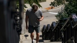 A pedestrian uses his phone in Kilbourn Reservoir Park Wednesday, Sept. 8, 2021, in Milwaukee. (AP Photo/Morry Gash)