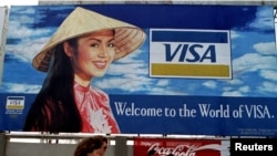 FILE - Tourists walk past advertisements of foreign companies near the airport of Ho Chi Minh City (formerly Saigon) March 8, 1994.