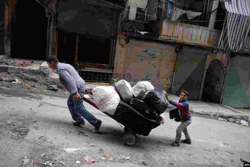 Young Syrians drag a cart as they leave Sheikh Maqsud neighborhood in Aleppo. 