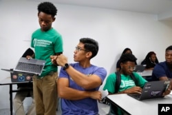 Tamar Champion, 14, left, gets a "fist bump" from teacher Enrique Ramos, as he shows his teacher his results after taking a diagnostic test using special software in his literacy studio class at the Washington Leadership Academy, Aug. 23, 2017, in Washington.