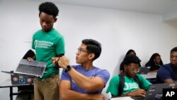 Tamar Champion, left, gets a "fist bump" from teacher Enrique Ramos, as he shows his teacher his results after taking a test using special software in his literacy studio class at the Washington Leadership Academy, Aug. 23, 2017. (AP Photo/Jacquelyn Martin) 