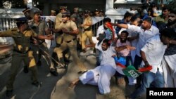 A police officer wields his stick against the members of Kerala Students Union, the student wing of India's main opposition Congress party, outside a police station during a protest in Kochi, India, Jan. 3, 2019.