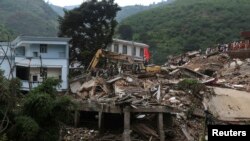 铲土机在云南昭通鲁甸县的地震灾区现场清除废墟，寻找遇难者遗体。（2014年8月5日）