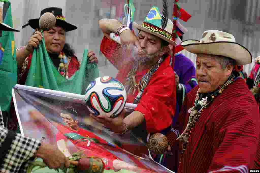 Peruvian shamans perform a ritual while holding the official ball for the 2014 World Cup and a poster of Portugal&#39;s soccer player Cristiano Ronaldo at the National Stadium in Lima, June 10, 2014.