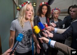 FILE - Leader of the feminist protest group Femen, Ukrainian Inna Shevchenko, left, speaks to the media as she and other members of the group arrive at courhouse in Paris, July 9, 2014.