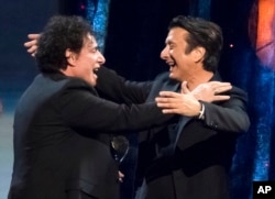 Inductees Neal Schon, left, and Steve Perry from the band Journey embrace at the 2017 Rock and Roll Hall of Fame induction ceremony.