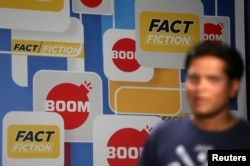 A crew member walks in front of a hoarding displaying the logo of BOOM, one of Facebook Inc's fact-checking partners in India, at a studio in Mumbai, India, March 12, 2019.