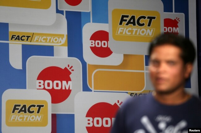 A crew member walks in front of a hoarding displaying the logo of BOOM, one of Facebook Inc's fact-checking partners in India, at a studio in Mumbai, India, March 12, 2019.