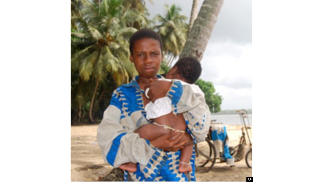 An Ivorian boy holds his baby brother at the Koblakan river crossing in Liberia