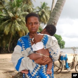 An Ivorian boy holds his baby brother at the Koblakan river crossing in Liberia