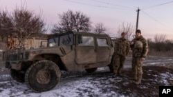 In this Jan. 20, 2022, photo, Ukrainian soldiers stand at their Hamvee on the line of separation from pro-Russian rebels, Mariupol, Donetsk region, Ukraine.