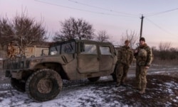 Ukrainian soldiers stand at their Humvee at the line of separation from pro-Russian rebels, near Mariupol, Donetsk region, Ukraine, Jan. 20, 2022.