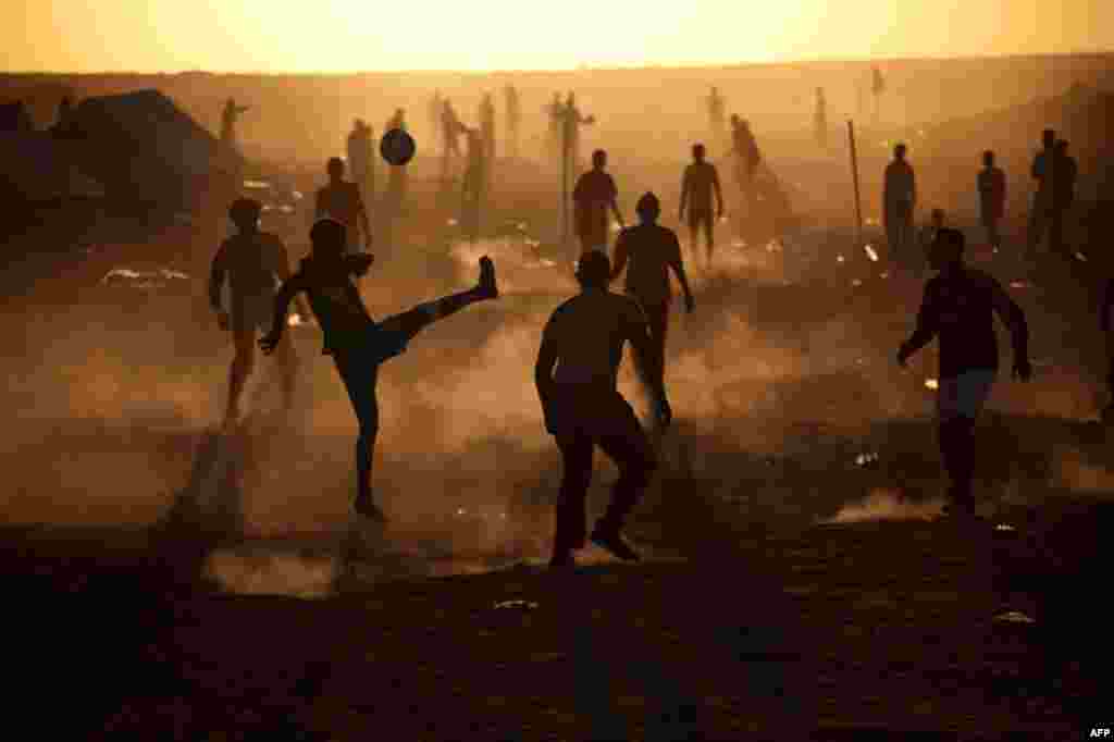 Men, who used to work in Libya and fled the unrest in the country, play football in a refugee camp at the Tunisia-Libyan border, in Ras Ajdir, Tunisia, Thursday, March 17, 2011. More than 250,000 migrant workers have left Libya for neighboring countries, 