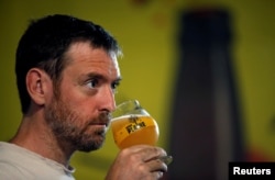 FILE - A worker tastes the liquid from a mash tun during the beer brewing process at the "La Plaine" microbrewery in Marseille, France, June 6, 2018.