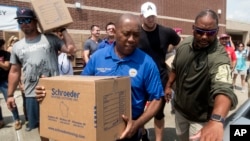 El alcalde de Houston, Sylvester Turner, de camisa azul, participa en una entrega de víveres a los damnificados del huracán Harvey, organizada por el jugador de fútbol americano J.J. Watt (de camisa negra).