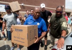 Houston Mayor Sylvester Turner, center, with Houston Texans Shane Lechler, left, and J.J. Watt, second right, distribute relief supplies to people impacted by Hurricane Harvey on Sunday, Sept. 3, 2017, in Houston.