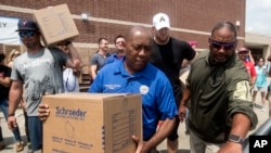 Houston Mayor Sylvester Turner, center, with Houston Texans Shane Lechler, left, and J.J. Watt, second right, distribute relief supplies to people impacted by Hurricane Harvey on Sunday, Sept. 3, 2017, in Houston.