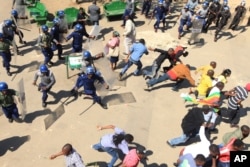Zimbabwe Protests: Zimbabwean riot police clash with protestors during a demonstration against the introduction of bond notes by the Reserve Bank of Zimbabwe, in Harare, Wednesday, Aug. 17, 2016.