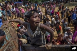 A Rohingya Muslim boy, who crossed over from Myanmar into Bangladesh, pleads with aid workers to give him a bag of rice near Balukhali refugee camp, Bangladesh, Thursday, Sept. 21, 2017.