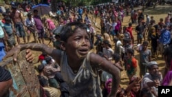 A Rohingya Muslim boy, who crossed over from Myanmar into Bangladesh, pleads with aid workers to give him a bag of rice near Balukhali refugee camp, Bangladesh, Thursday, Sept. 21, 2017.