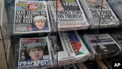Newspapers fronted with photos of British Prime Minister Theresa May and others are displayed at a shop in Westminster in London, June 10, 2017. May has been criticized as too detached at times.