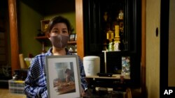 Kaori Takada poses with her brother's photo in front of her family altar at her home in Matsubara, south of Osaka, western Japan, Nov. 16, 2021.