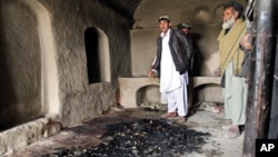 Men stand next to blood stains and charred remains inside a home where witnesses say Afghans were killed by a U.S. soldier in Panjwai, Kandahar province, south of Kabul, Afghanistan, March 11, 2012
