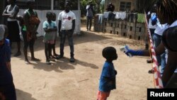 Seorang petugas memeriksa suhu tubuh seorang anak untuk mendeteksi kemungkinan terpapar ebola di distrik Paynesville, Monrovia, Liberia (foto: dok).