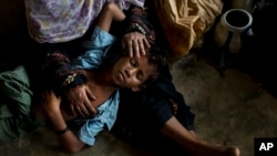 A Rohingya woman comforts her exhausted son as they take shelter inside a school after having just arrived from the Myanmar side of the border at Kutupalong refugee camp, Bangladesh, Sept. 7, 2017.