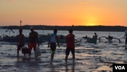 At sunset on the shores of Masinloc town fishermen return from a day of fishing nearby in the South China Sea, while others head out for overnight fishing, Masinloc, Philippines, Nov. 8, 2015. (S. Orendain/VOA)
